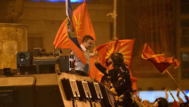 Янко Бачев върху бронирания автомобил с руското знаме в едната ръка, а в другото с македонското