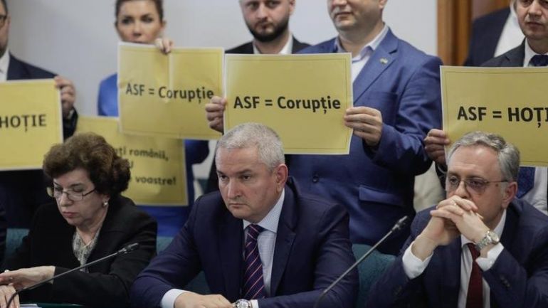 Депутатите от румънската дясна и популистка партия AUR Алианс за Съюза на румънците държат транспаранти с надписи „ASF – корупция“ и „ASF – крадци“.