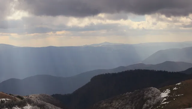 Слънцето се показва иззад облаци, все още топло с дъжд над Родопите